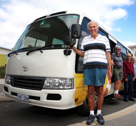 An elderly man standing next to retirement village bus