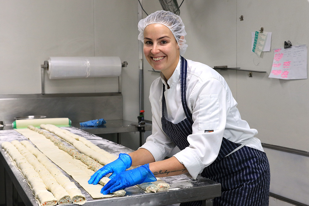 A chef rolling pastries in an industrial kitchen