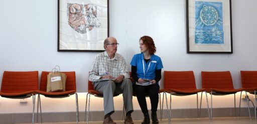 Older man sitting with Expo worker on chairs